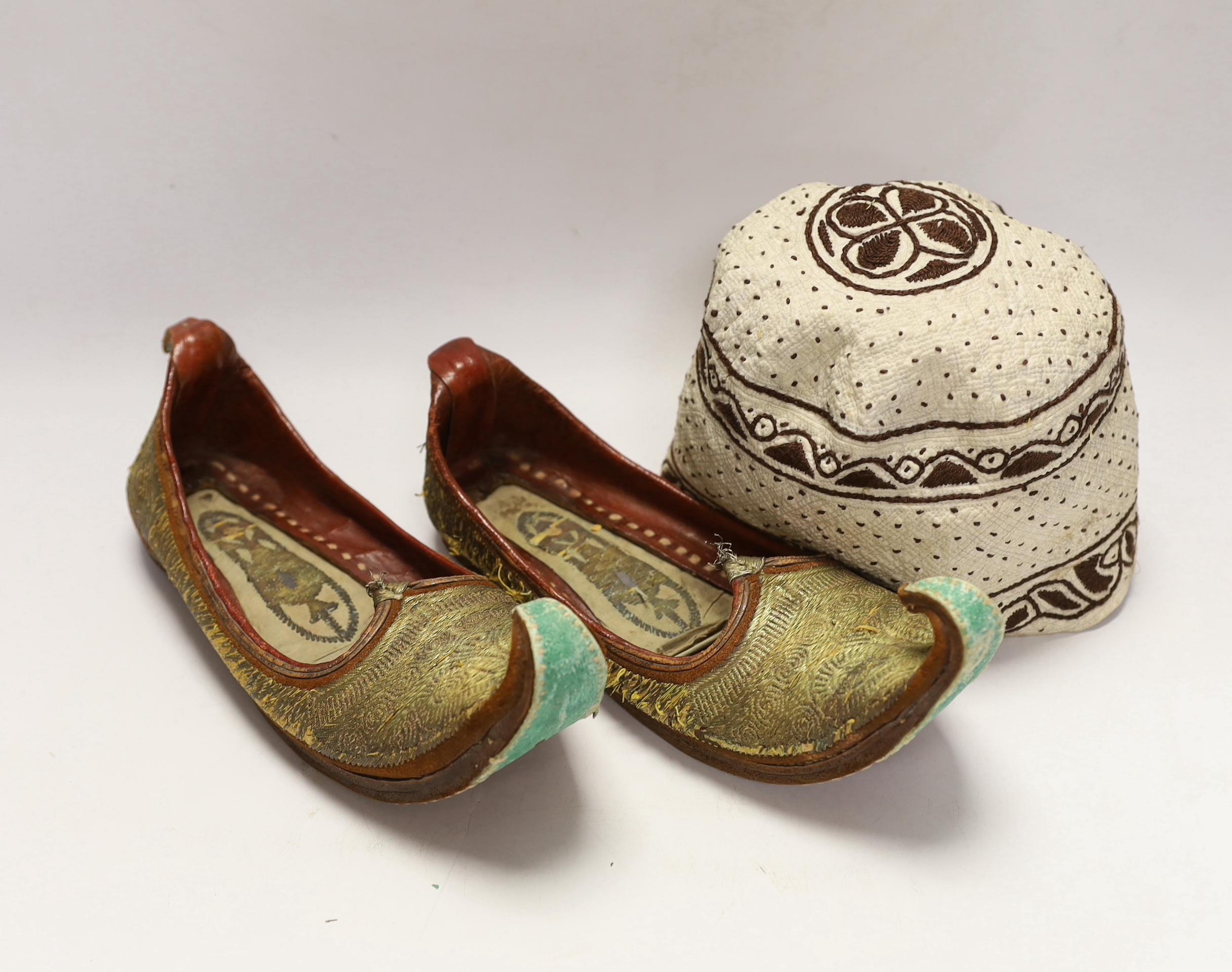 A pair of early 20th century metal thread embroidered Turkish slippers, a pair of similar embroidered red velvet children’s Indian slippers, an embroidered chain stitch drawstring purse and a quilted child’s hat